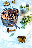 Boiled mushrooms in a sieve in a copper scoop, fresh mushrooms and fresh sage