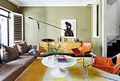 Cognacfarbene Lederstühle, Klassikertisch, Sofa und Sideboard im Wohnzimmer mit grünen Wänden