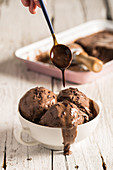 Chocolate sauce being drizzled over chocolate ice cream