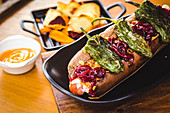 Hot Dog mit sonnengetrockneten Chilis serviert mit Gemüsechips