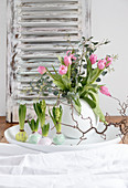 Spring arrangement of tulips in spherical vase and hyacinths with waxed bulbs