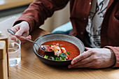 Person isst Meeresfrüchtesalat mit Brunnenkresse und roter Sauce