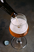 Bier wird aus Flasche in Bierglas eingeschenkt