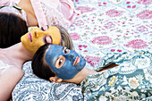 Women laying down with colourful face masks
