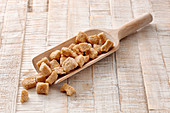 Brown sugar cubes on a wooden scoop