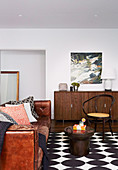 Vintage Ledercouch, Couchtisch, Stuhl und Sideboard im Wohnzimmer mit schwarz-weißem Teppich