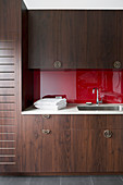 Fitted wardrobe with dark fronts and red back wall in the bathroom
