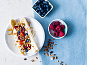 Healthy banana split with yogurt, granola, berries, and honey drizzle