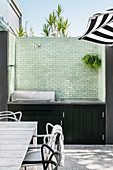 Outdoor-Küche mit grüner, gefliester Wand auf der Terrasse