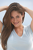 A young brunette woman on a beach wearing a beige top