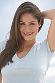 A young brunette woman on a beach wearing a beige top