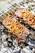 Beef steaks with onions on a grill rack
