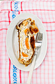 A piece of curd strudel with apricots and poppy seeds on a plate