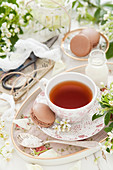 Eine Tasse Tee serviert mit Schokoladenmacarons