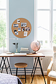 Round cork pinboard above desk on trestles