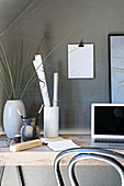 Vases holding glasses and used as desk organisers next to laptop