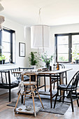 High chair, black chairs and bench around rustic dining table