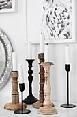 White candles in various wood and metal candlesticks