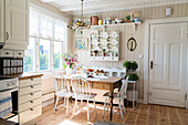 Rustic table, bench and chairs next to window in bright kitchen-dining room