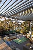 Outdoor furniture on terrace with pergola and glass balustrade