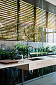 Elegant sink unit with integrated sink against glass wall with louvre blinds