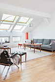 Grey sofa, coffee table, leather armchair and footstool in attic living room