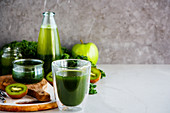 Green detox smoothies for breakfast in front of a grey background