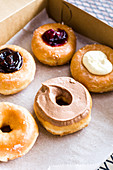 A cardboard box of handmade, local donuts with chocolate frosting, glazed, jelly and cream-filled