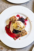 Baked shortbread with seeds topped with rich berry compote, syrup and vanilla ice cream with crumbs
