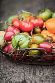 A basket filled with different types of tomatoes
