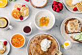 Gesundes Frühstück mit Porridge, Pancakes, Himbeeren und Snacks
