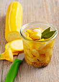 Pickled yellow courgettes with bay leaves, mustard, vinegar and sugar in a jar