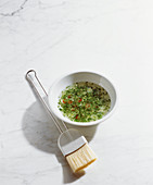 Herb grill marinade with chilli in a bowl with a brush