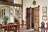 A pair of old, wooden, double Chinese doors in living room with dining table, wooden chairs and drawings on wall