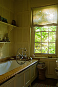 Antique, wood clad bathtub and wooden panelling in bathroom with lattice window