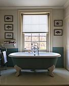 Free-standing, claw-footed blue bathtub in bathroom of period building