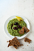Spinach hummus with black olives and bread