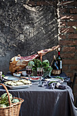 Gedeckter Tisch mit Rotwein, Artischocken und Serranoschinken