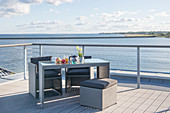 Grey outdoor furniture on open terrace with wooden deck and sea view