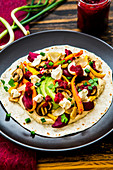 Tortilla with hummus, oven-roasted vegetables, avocado, crème fraîche and beetroot pesto