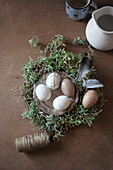 Speckled eggs on pewter plate in Easter nest decorated with feathers