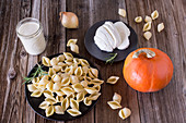 Ingredients for vegetarian pumpkin dishes with pasta and mozzarella on a wooden surface