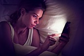 Young woman using digital tablet in bed