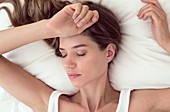 Young woman lying in bed with closed eyes