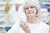 Senior woman holding pill bottle in pharmacy