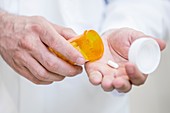 Pharmacist pouring pill into hand