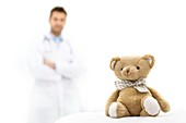 Teddy bear with doctor in background