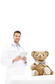 Teddy bear with doctor in background