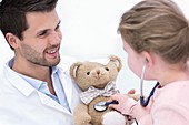 Girl playing with teddy bear and stethoscope