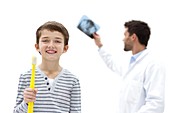 Boy holding over sized toothbrush in dental surgery